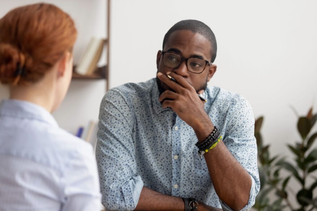 A man sits across from a woman, looking thoughtful.