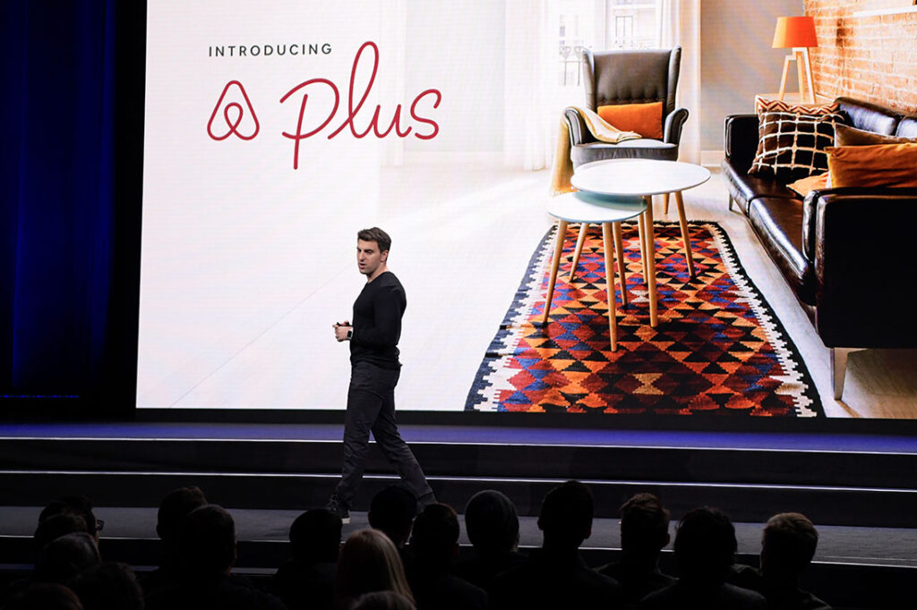 brian chesky on stage with Airbnb presentation backdrop