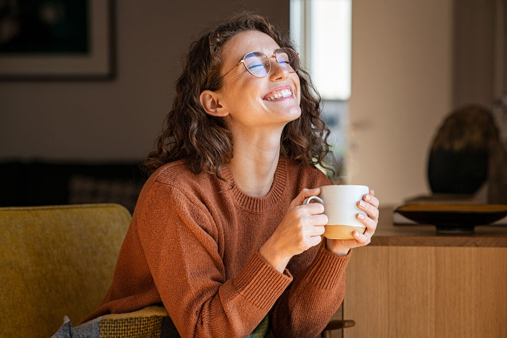 joyful young woman enjoying a cup of coffee at home