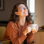 joyful young woman enjoying a cup of coffee at home