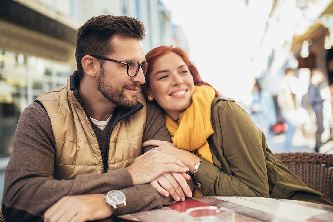 young couple in love sitting at the cafe table outdoors