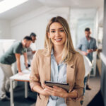 Smiling confident business leader looking at camera and standing in an office at team meeting