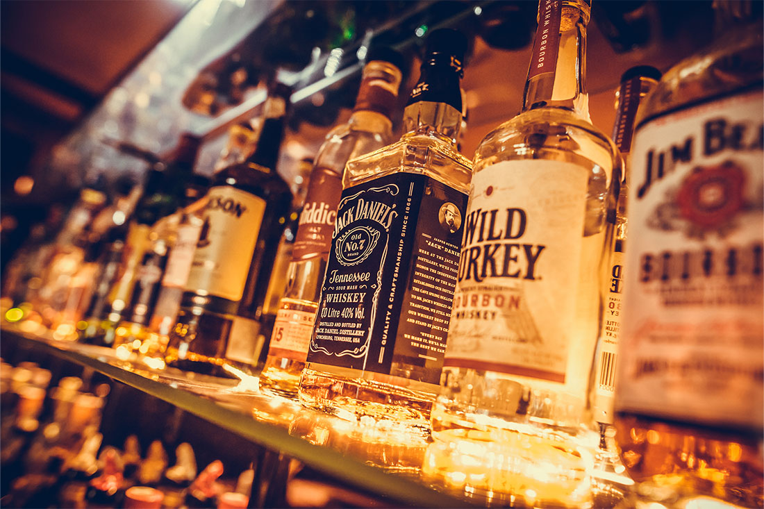 alcohol bottles in a row, displayed in a bar or restaurant