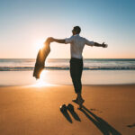 man with open arms enjoying beach landscapes