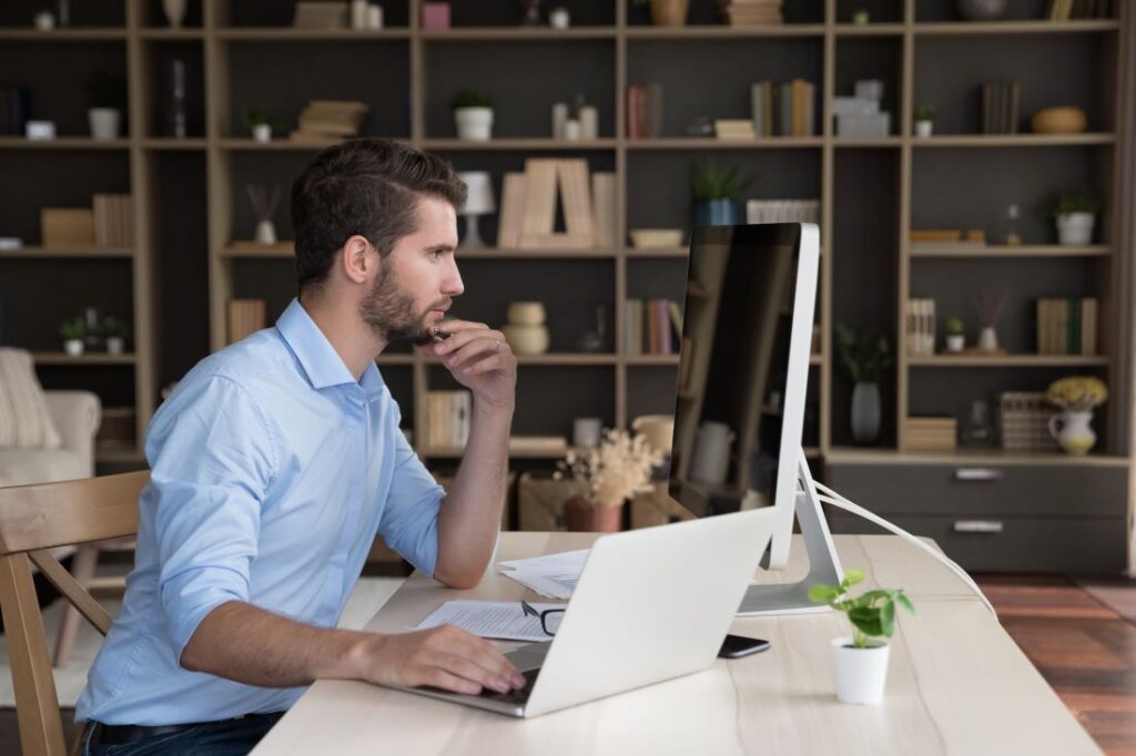 A male hiring manager looks over application materials on a computer.