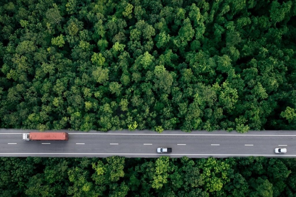 cars and a truck on a highway that is surrounded by trees