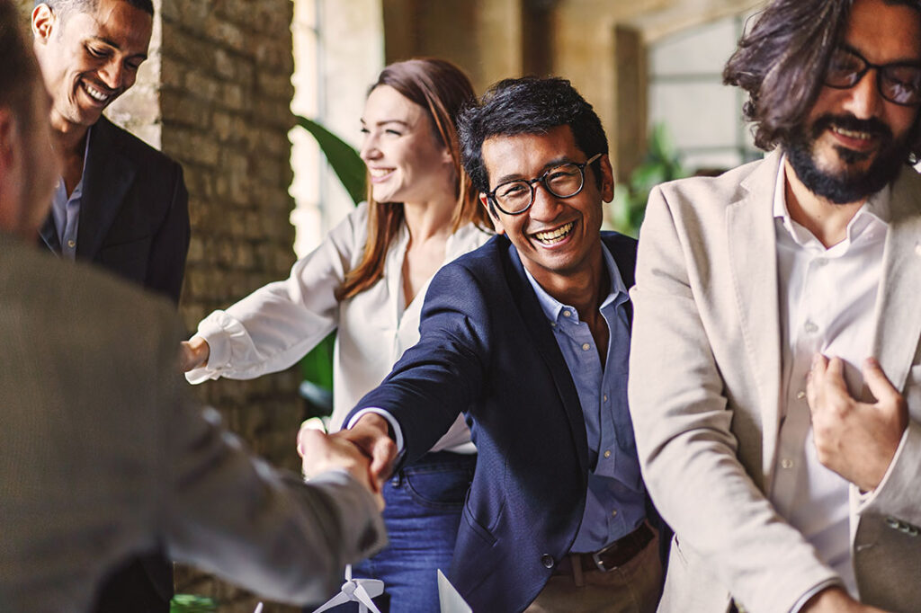 Group of diverse professionals celebrating with a handshake at a corporate event