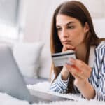 Young woman holding credit card and using laptop computer