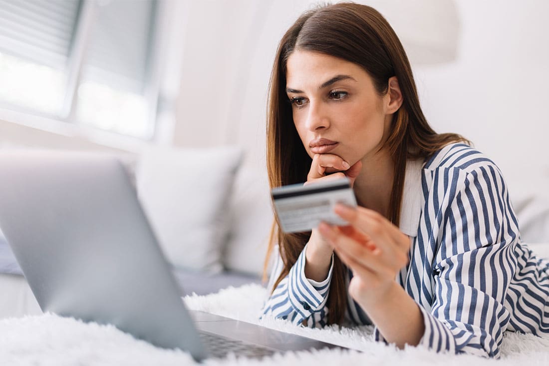 Young woman holding credit card and using laptop computer