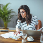 A business woman with tax paperwork on desk with laptop