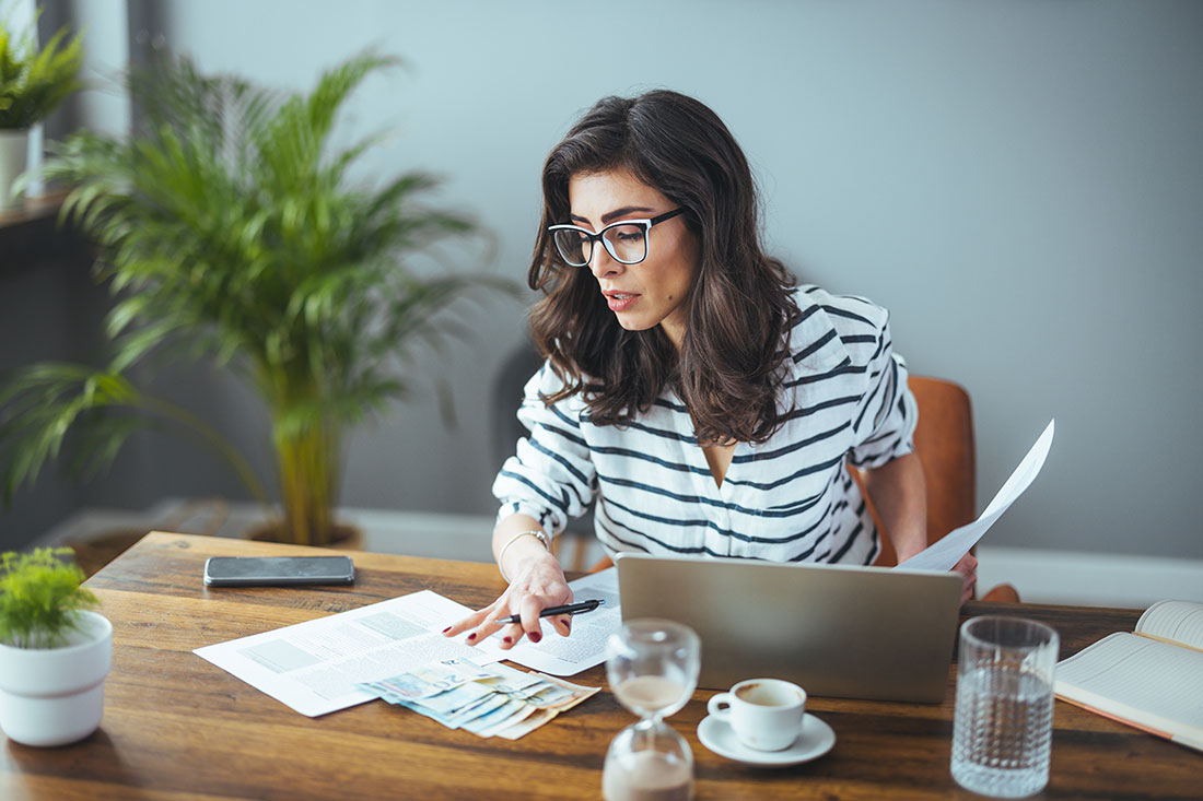 A business woman with tax paperwork on desk with laptop