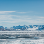 A landscape view of the Arctic, covered in ice, with mountains in the background.