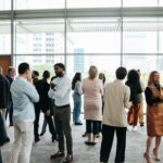 A group of people, professionally dressed, networking in an open room.