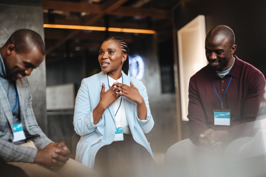 A woman sitting between two men, gesturing with her hands while she speaks.