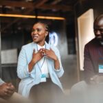 A woman sitting between two men, gesturing with her hands while she speaks.