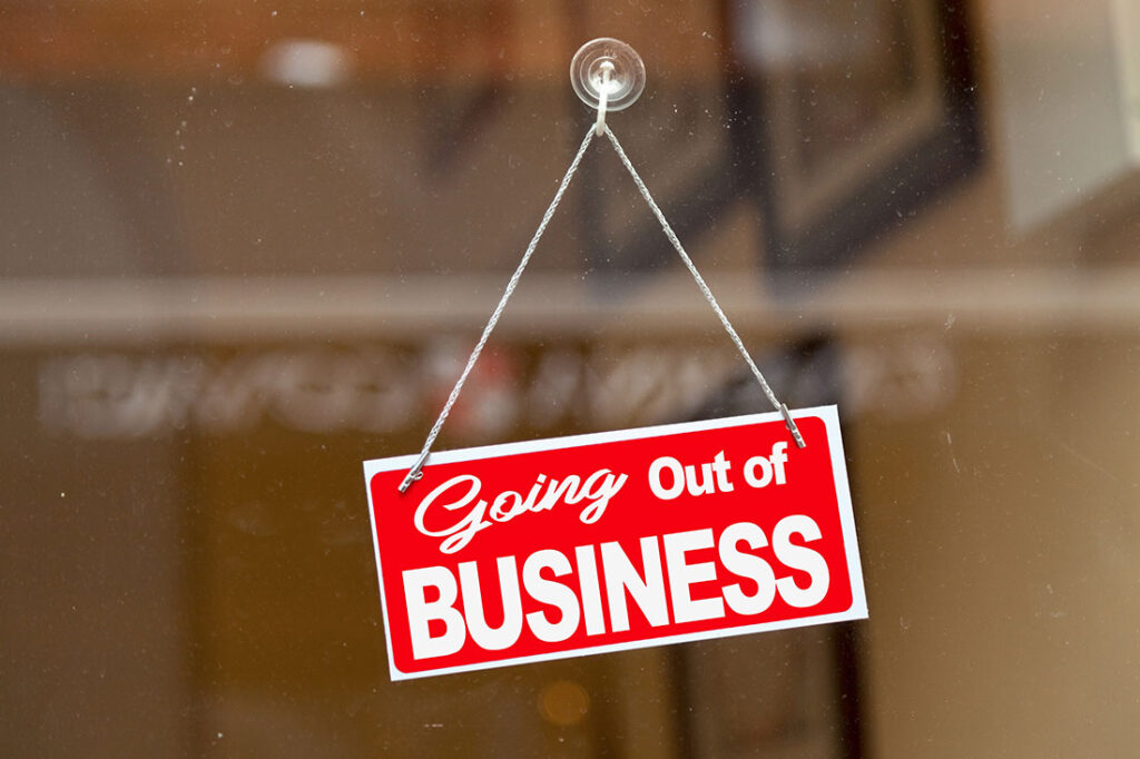 Red sign hanging at the glass door of a shop saying: "Going out of business".